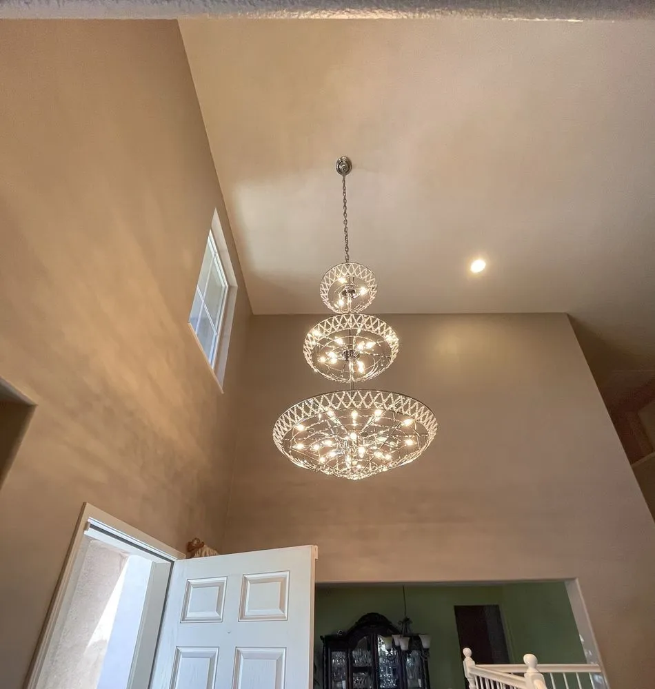 Two-tier crystal chandelier and recessed lights in a two-story entryway.