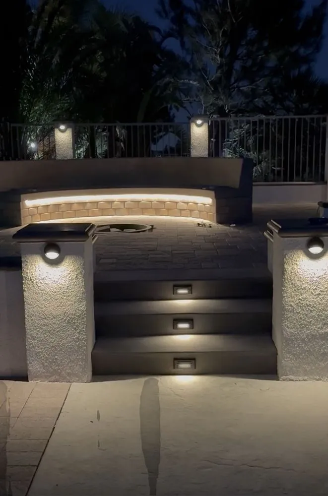 Patio steps at night lit by recessed step lights and sconces on the planter walls.